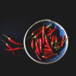 rote Chilis in einer blauen Keramikschale auf schwarzen Hintergrund