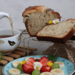 veganes Bananenbrot mit einer Tasse Tee und Teller voller Obst