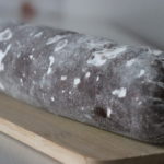 chocolate salami in a peace covered with powdered sugar on a wooden plate